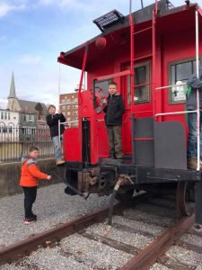 boys stand on and near a caboose